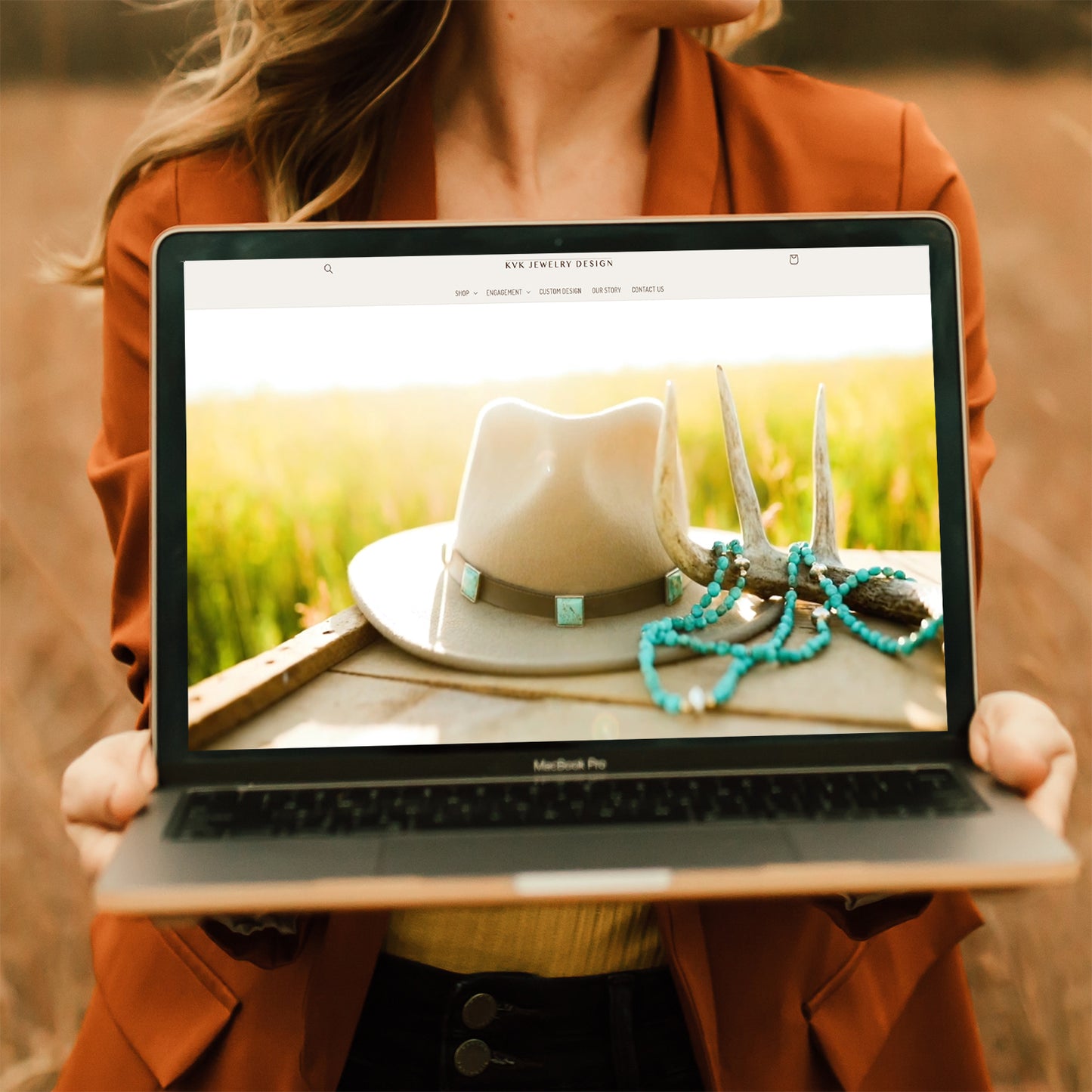 Woman holding open a computer with KVK Jewelry Design website open.