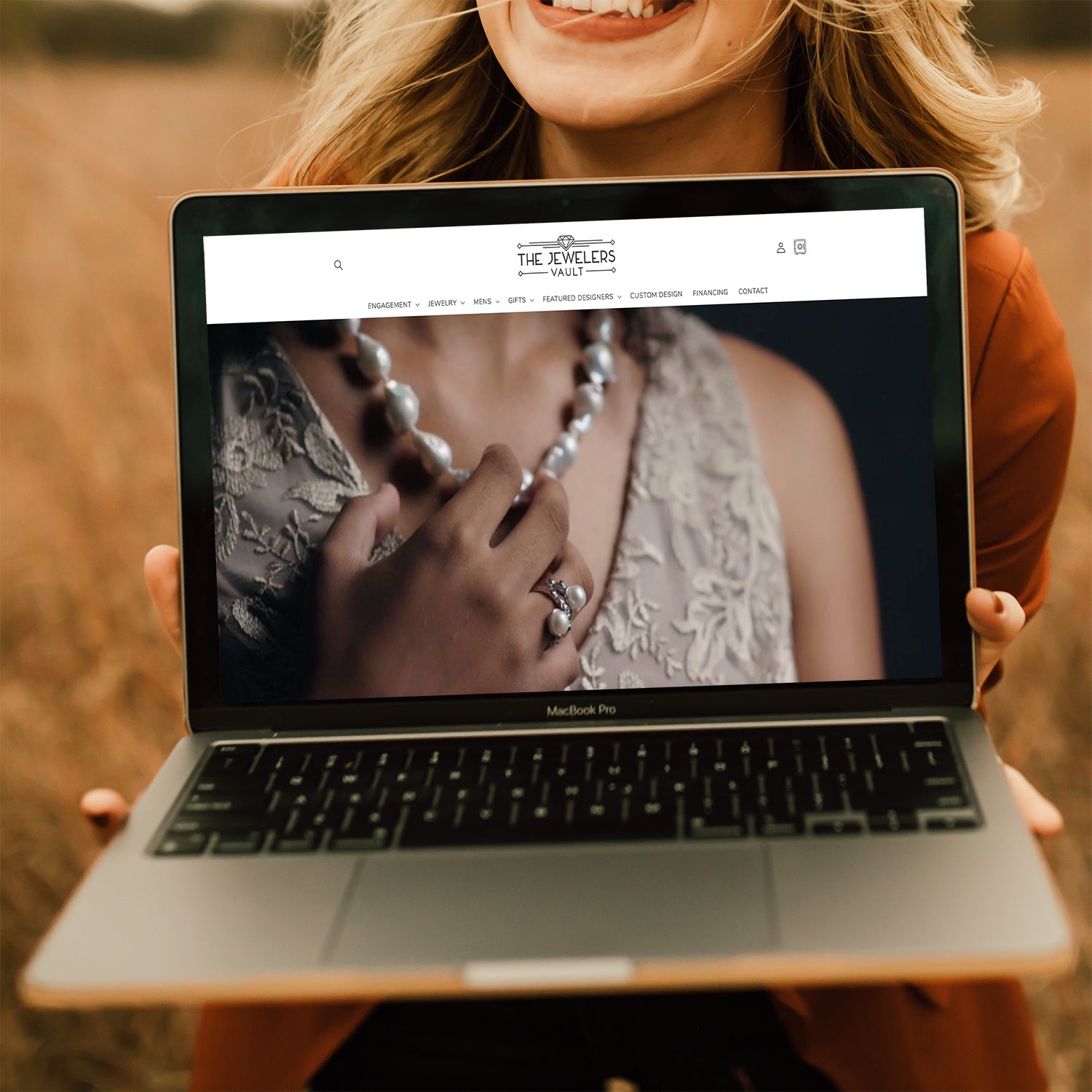 Woman holding open a laptop with the homepage of The Jewelers Vault on the screen.